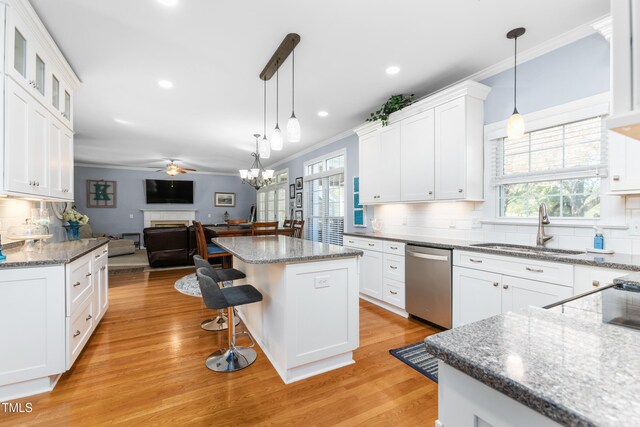 kitchen featuring dishwasher, light hardwood / wood-style flooring, sink, a center island, and white cabinetry