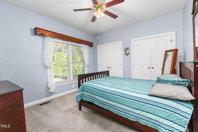 carpeted bedroom with two closets and ceiling fan