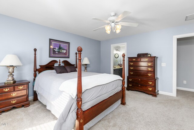 bedroom featuring light carpet, ceiling fan, and ensuite bath