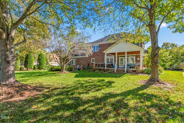 back of property with covered porch and a lawn