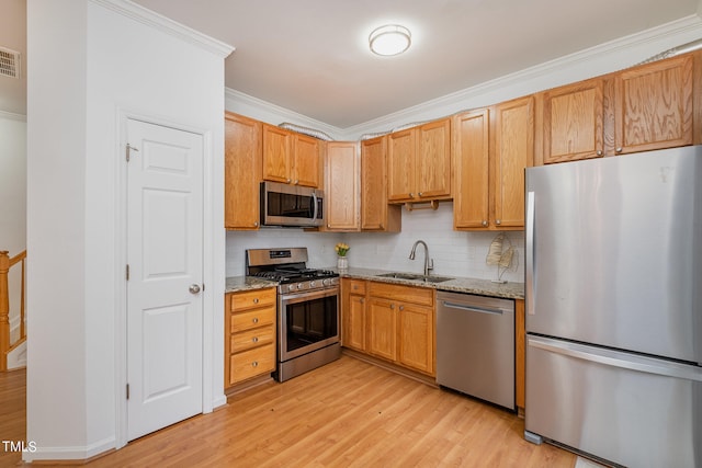 kitchen featuring sink, light stone countertops, ornamental molding, and appliances with stainless steel finishes