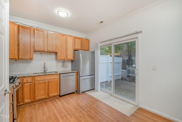 kitchen featuring light stone countertops, appliances with stainless steel finishes, decorative backsplash, sink, and light hardwood / wood-style flooring