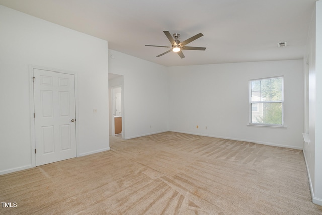 spare room featuring light carpet, vaulted ceiling, and ceiling fan