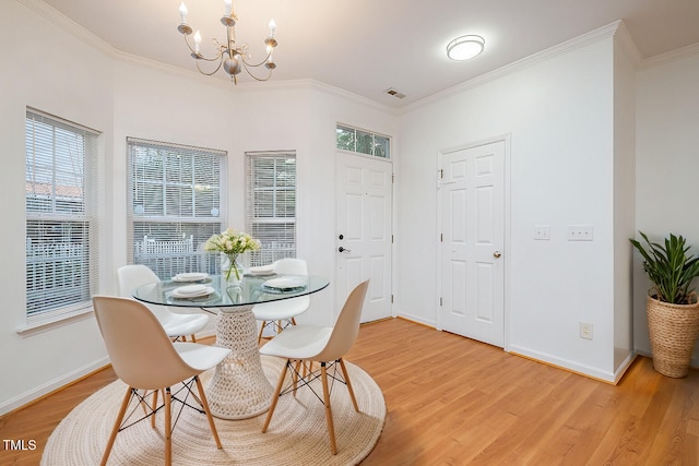 dining space with hardwood / wood-style flooring, ornamental molding, and an inviting chandelier