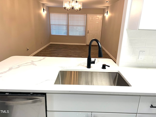 kitchen featuring an inviting chandelier, wood-type flooring, sink, light stone countertops, and stainless steel dishwasher