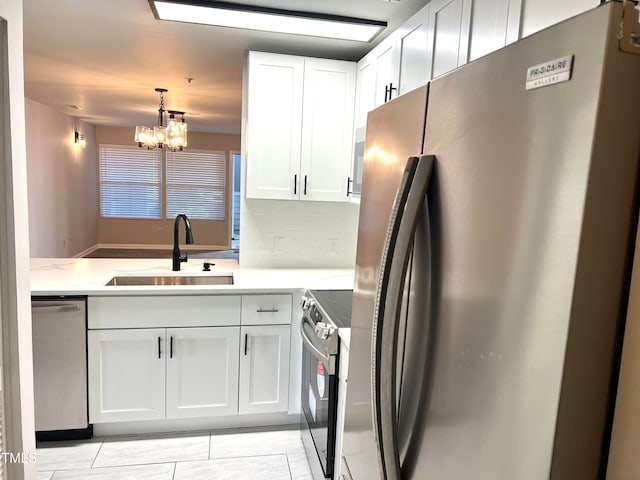 kitchen with stainless steel appliances, white cabinets, sink, a notable chandelier, and decorative light fixtures