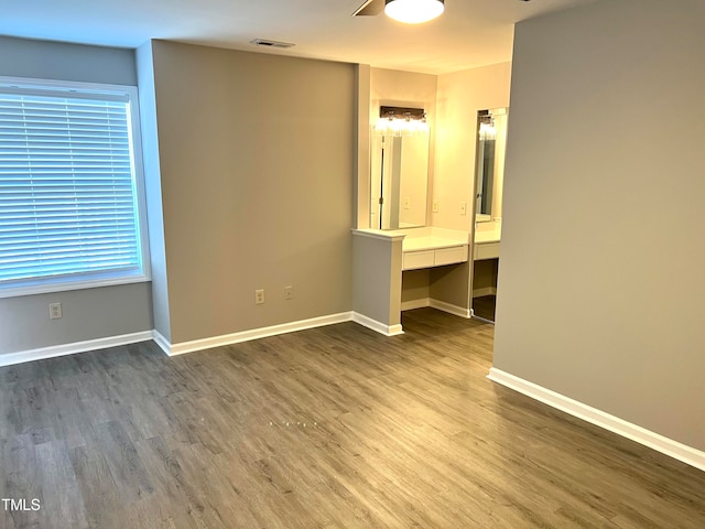 unfurnished bedroom featuring ceiling fan, built in desk, and hardwood / wood-style floors