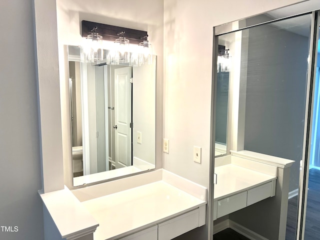 bathroom with vanity, toilet, and wood-type flooring