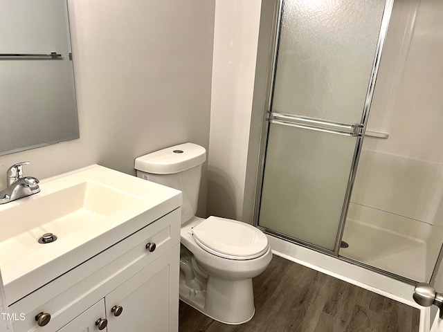 bathroom with wood-type flooring, a shower with door, vanity, and toilet