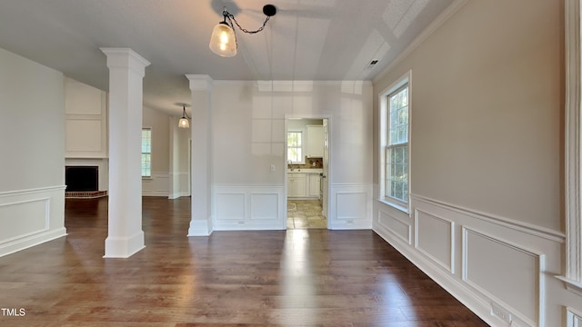 interior space with dark wood-type flooring, ornate columns, and ornamental molding