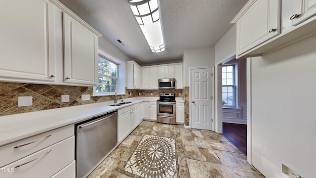 kitchen featuring stainless steel appliances, backsplash, white cabinets, and sink