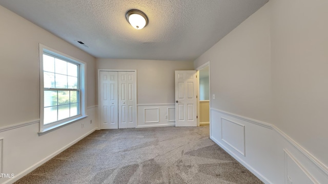 unfurnished bedroom featuring a closet, a textured ceiling, and light carpet