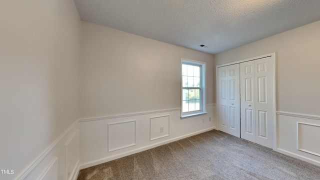 unfurnished bedroom featuring a closet, carpet, and a textured ceiling