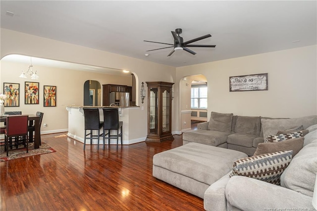 living room with ceiling fan with notable chandelier and dark hardwood / wood-style floors