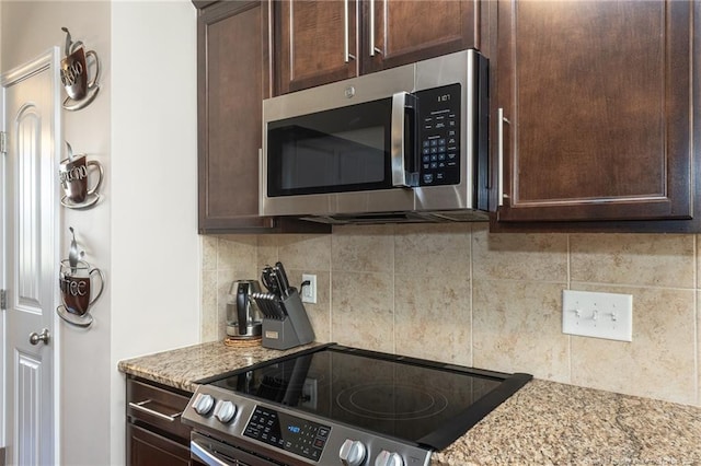 kitchen featuring dark brown cabinets, light stone countertops, range, and decorative backsplash