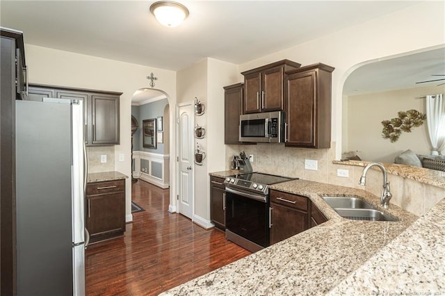 kitchen with tasteful backsplash, dark hardwood / wood-style flooring, sink, stainless steel appliances, and light stone countertops