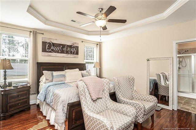 bedroom featuring dark wood-type flooring, a raised ceiling, multiple windows, and ceiling fan