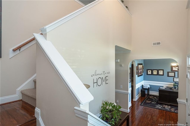 stairway featuring a towering ceiling and hardwood / wood-style flooring