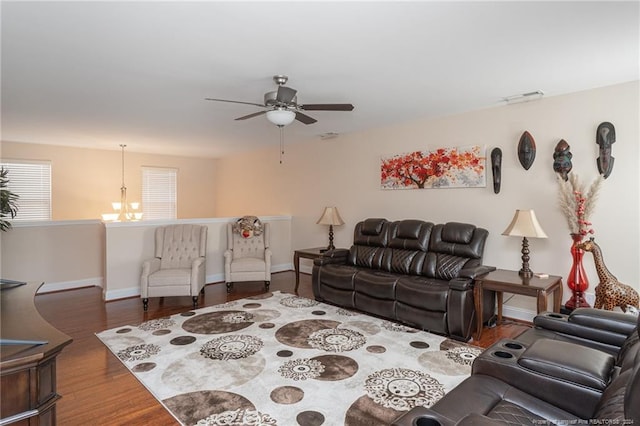 living room with ceiling fan with notable chandelier and dark hardwood / wood-style floors