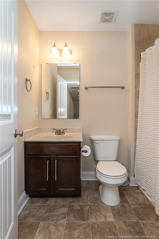 bathroom featuring a shower with curtain, vanity, and toilet