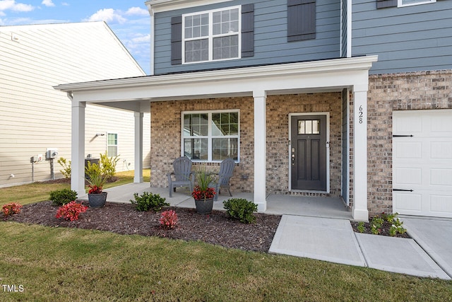 doorway to property with a garage, a lawn, and a porch