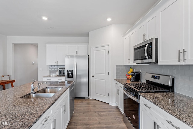 kitchen with dark stone countertops, sink, hardwood / wood-style floors, white cabinets, and appliances with stainless steel finishes