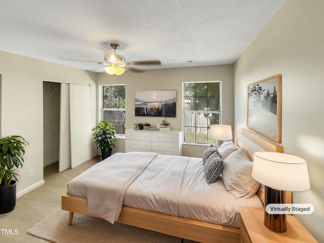 carpeted bedroom with ceiling fan, a textured ceiling, and multiple windows