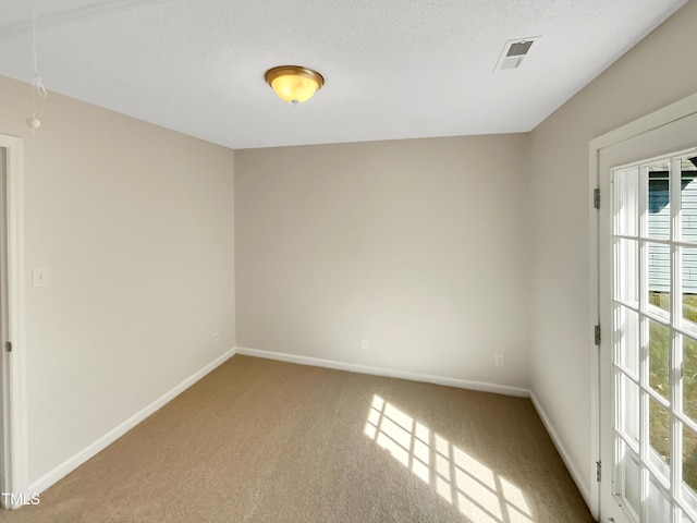 carpeted empty room featuring a textured ceiling