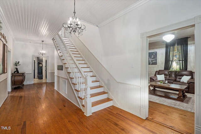 stairs with ornamental molding, a chandelier, and hardwood / wood-style floors