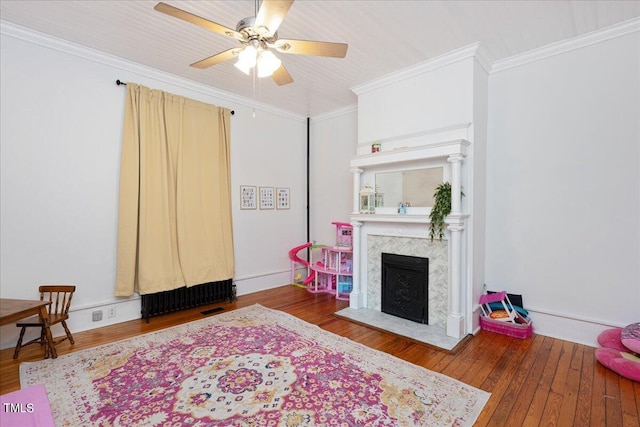 interior space with ceiling fan, ornamental molding, a premium fireplace, and dark hardwood / wood-style flooring