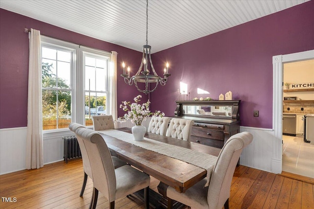 dining area featuring light wood-type flooring, a wealth of natural light, radiator heating unit, and a chandelier