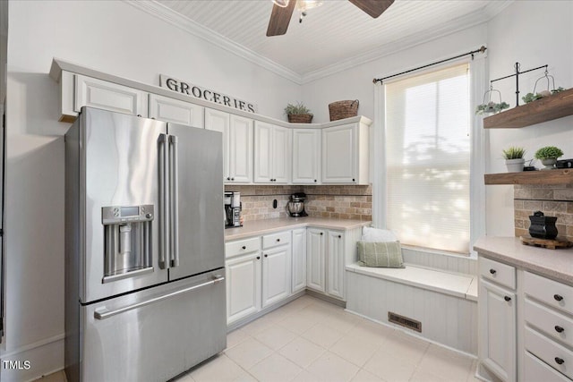 kitchen with ceiling fan, decorative backsplash, crown molding, white cabinetry, and stainless steel refrigerator with ice dispenser