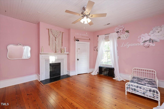 unfurnished living room featuring ceiling fan, hardwood / wood-style floors, and radiator heating unit