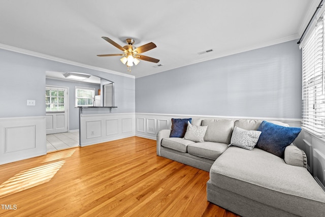 living room featuring ornamental molding, light hardwood / wood-style flooring, and ceiling fan