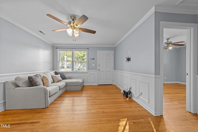 living room featuring crown molding, ceiling fan, and light hardwood / wood-style flooring