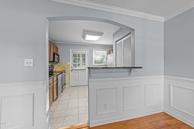 kitchen with black appliances, crown molding, and light hardwood / wood-style flooring