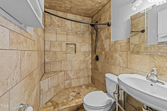 bathroom featuring sink, tiled shower, tile walls, toilet, and decorative backsplash