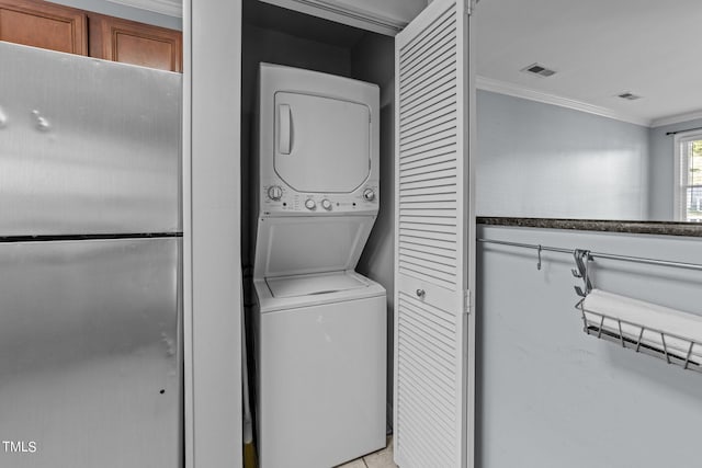 laundry room with ornamental molding and stacked washer and dryer