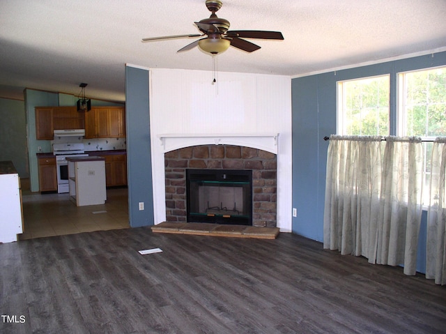 unfurnished living room featuring a fireplace, vaulted ceiling, dark hardwood / wood-style flooring, a textured ceiling, and ceiling fan