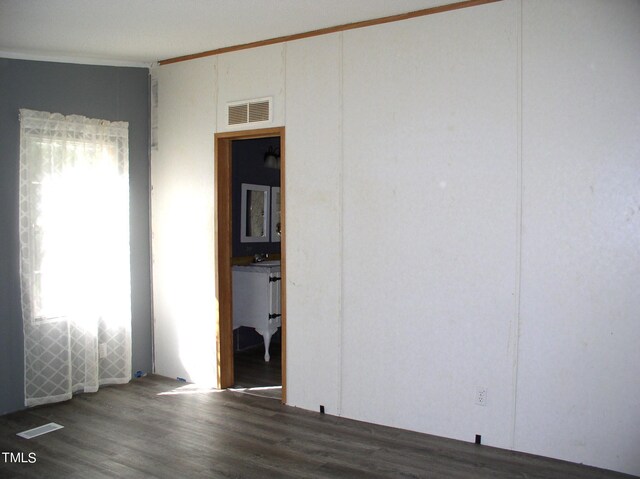 unfurnished room with a wealth of natural light, ornamental molding, and dark wood-type flooring