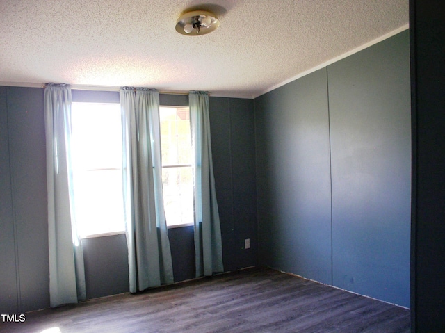 unfurnished room with a textured ceiling, a healthy amount of sunlight, and wood-type flooring