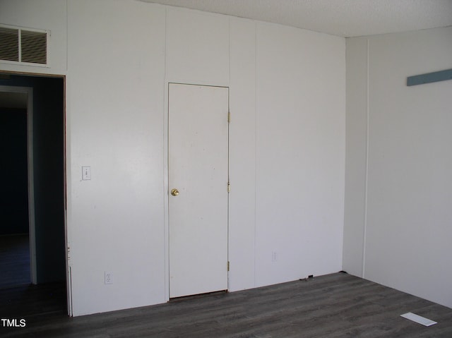 unfurnished bedroom featuring a textured ceiling and dark wood-type flooring