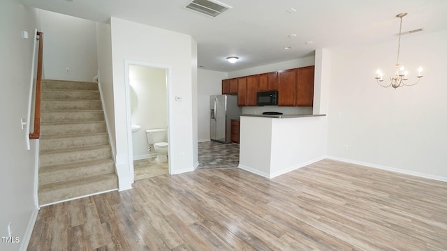 kitchen featuring kitchen peninsula, stainless steel fridge with ice dispenser, an inviting chandelier, light hardwood / wood-style flooring, and pendant lighting