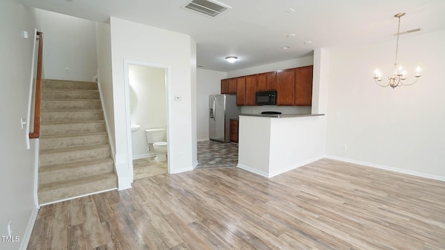 unfurnished living room with light wood-type flooring, visible vents, stairway, and an inviting chandelier