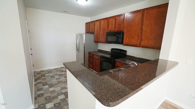 kitchen with a peninsula, a sink, baseboards, brown cabinets, and black appliances