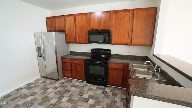 kitchen with dark countertops, a sink, and black appliances