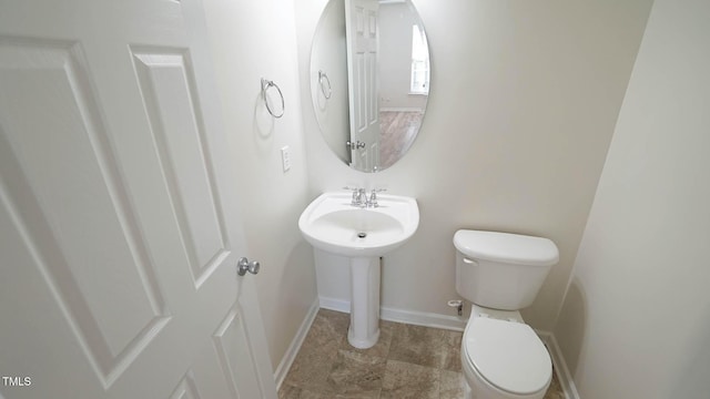 half bath featuring toilet and baseboards