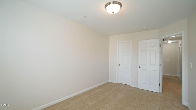 unfurnished bedroom featuring light colored carpet and baseboards