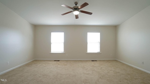 carpeted spare room featuring baseboards, a ceiling fan, and visible vents