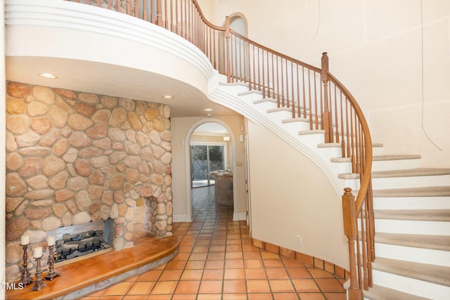 staircase featuring tile patterned flooring, a fireplace, and a high ceiling